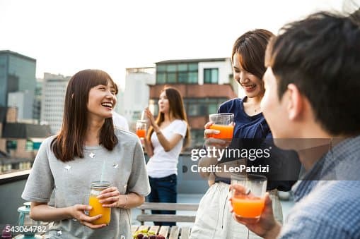 도심 옥상에서 음료를 들고 대화를 나누는 네 사람